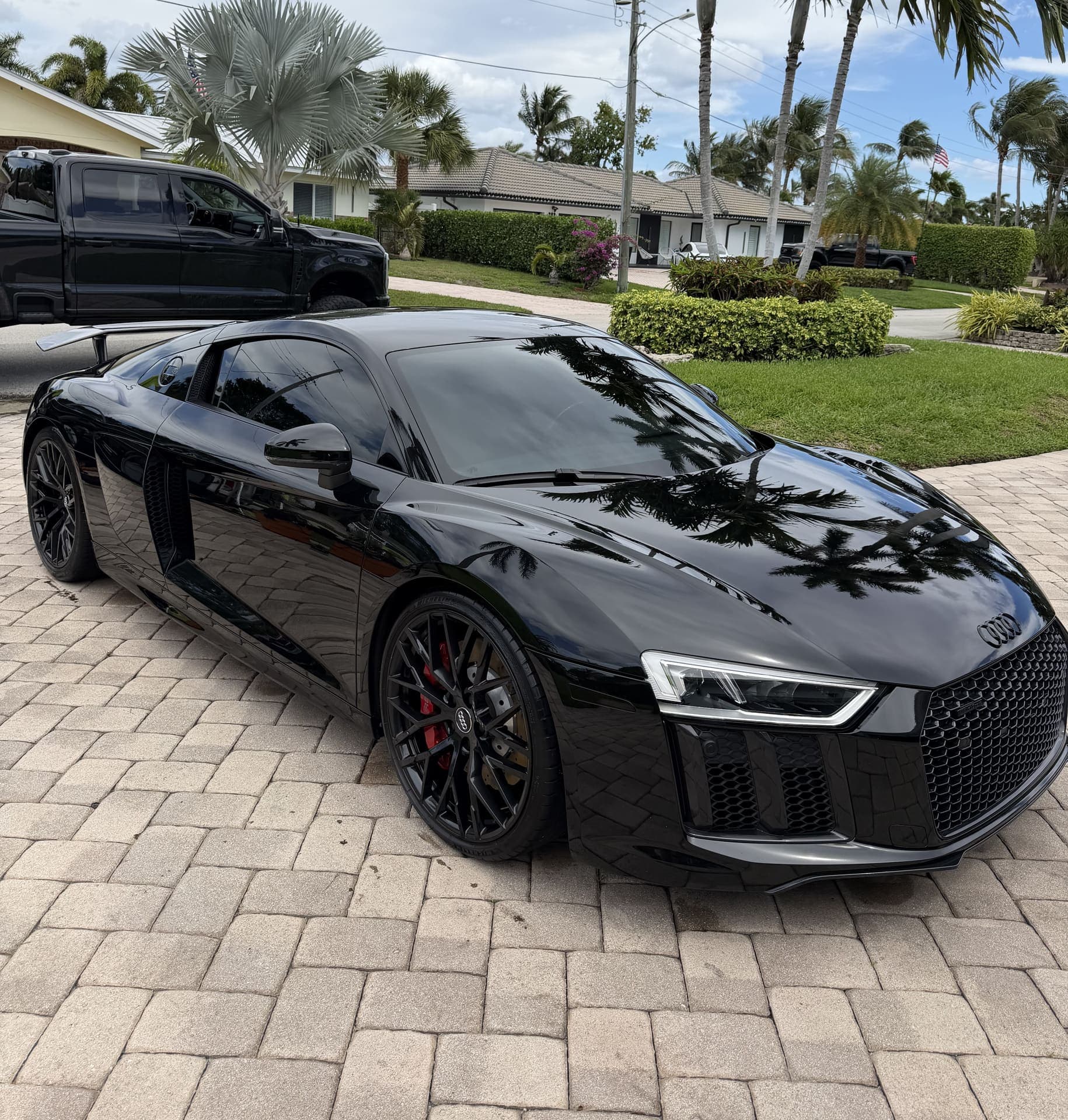 Black Audi R8 with a mirror finish on a paver driveway
